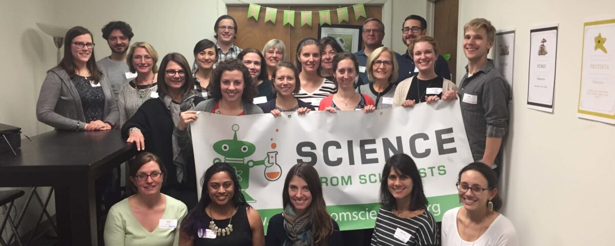 Massachusetts instructors holding a Science from Scientists banner at all staff training.