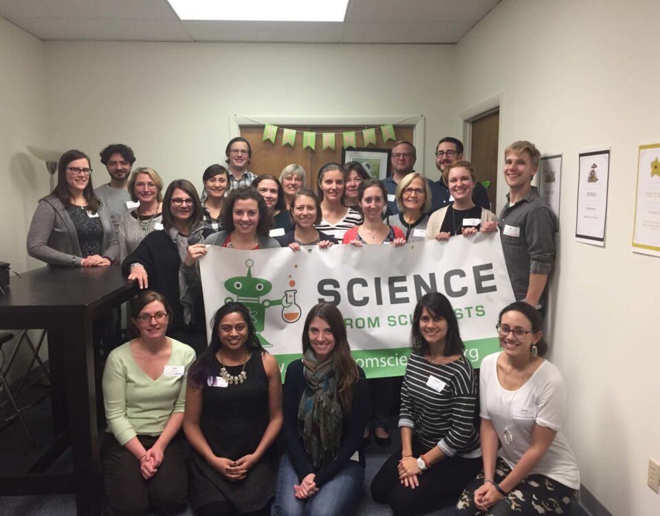 Massachusetts instructors holding a Science from Scientists banner at all staff training.