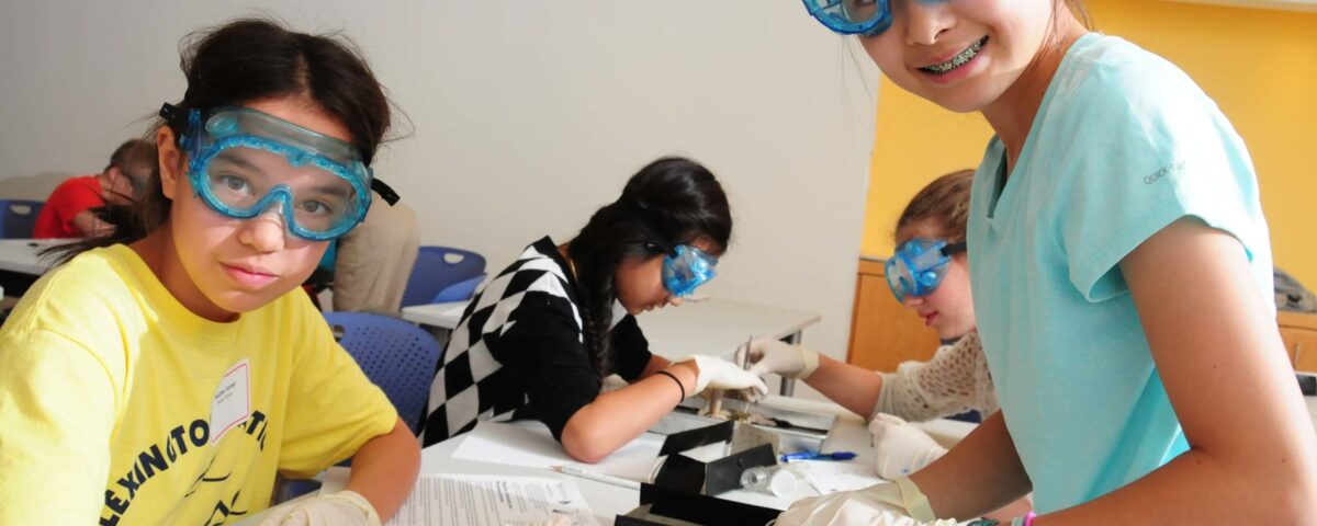 Students wearing googles and gloves dissecting a frog.