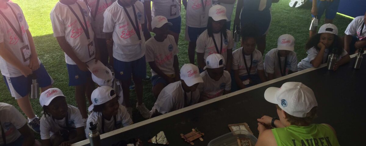 Staff member running experiment with students looking on.